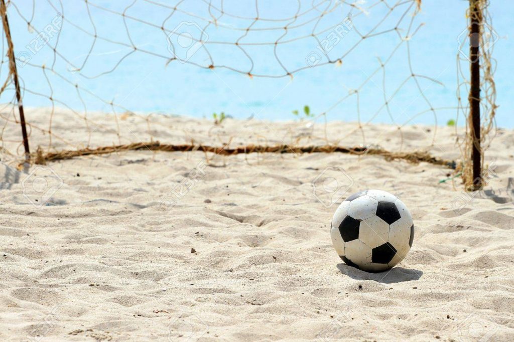 Soccar ball on sand infront of goals