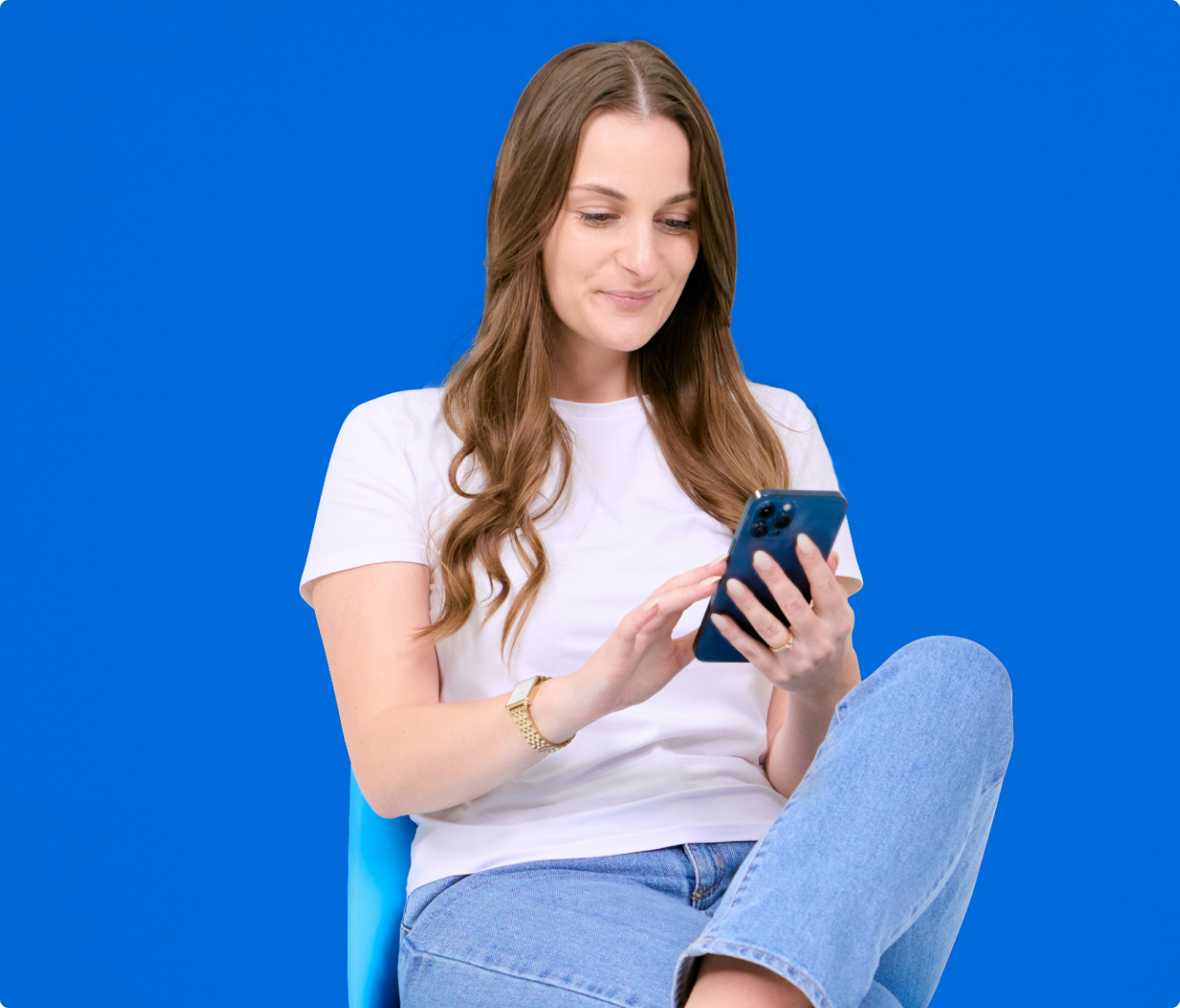 A woman sitting on a blue chair using a cell phone.