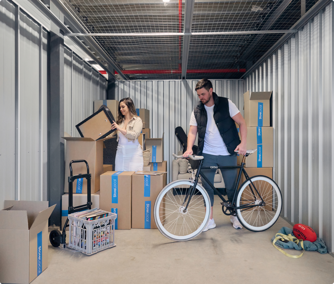 A man and woman standing in a storage room with a bicycle.