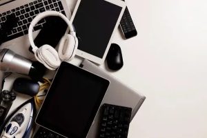 Old computers, digital tablets, mobile phones, many used electronic gadgets devices, cords, broken household and appliances on white background. Planned obsolescence, electronic waste for recycling